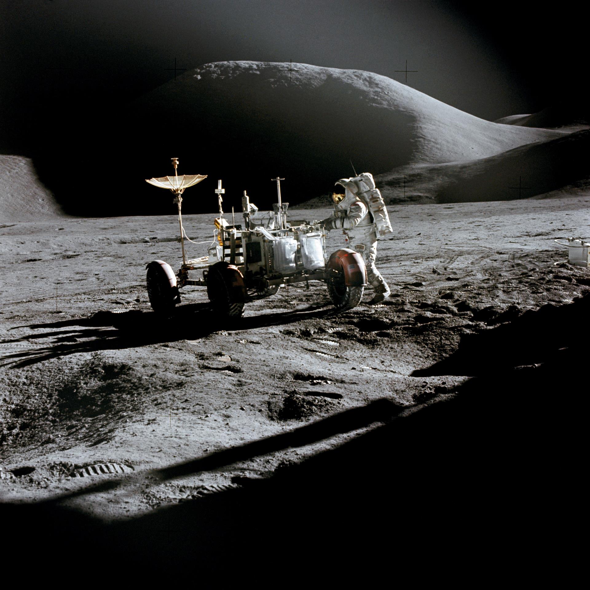 Astronaut working beside rover on moon