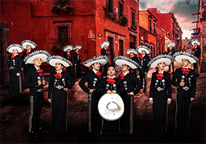 A mariachi band poses band members symmetrically in front of a dark red building.