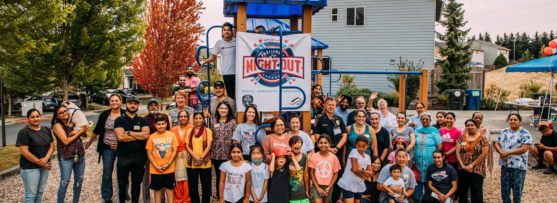 Community members gather with a uniformed officer at a playground.