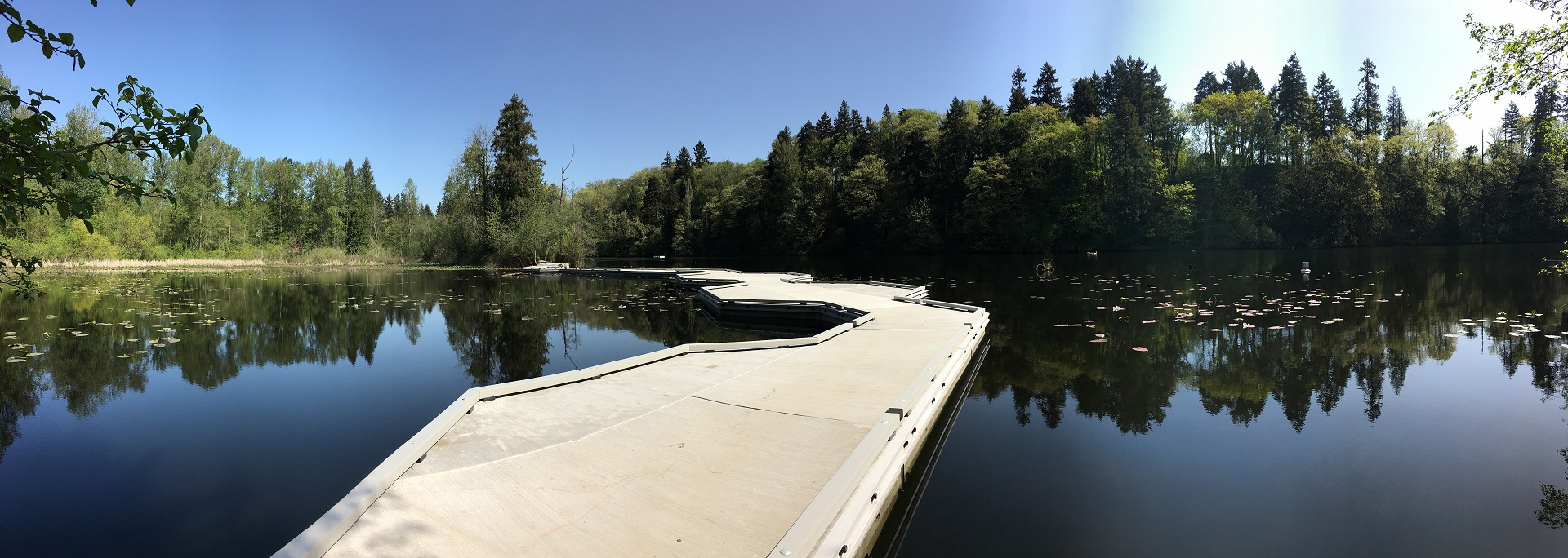 Floating concrete walkway across still lake water