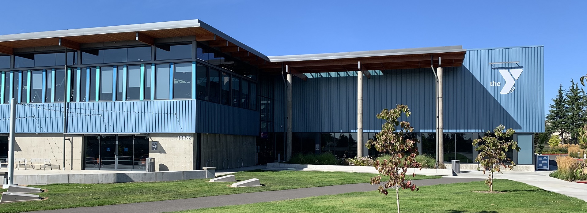 Main entry of the blue-walled YMCA in Kent, WA with grass lawn and entry plaza