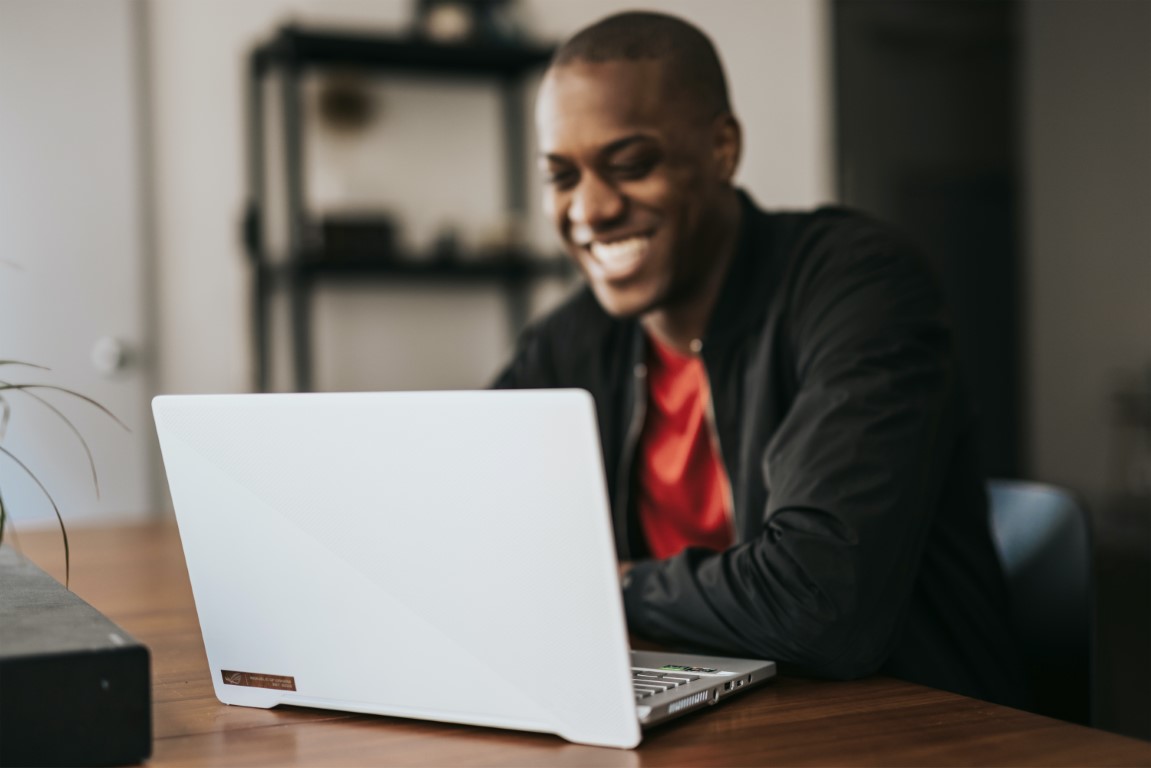 Person smiling behind a laptop